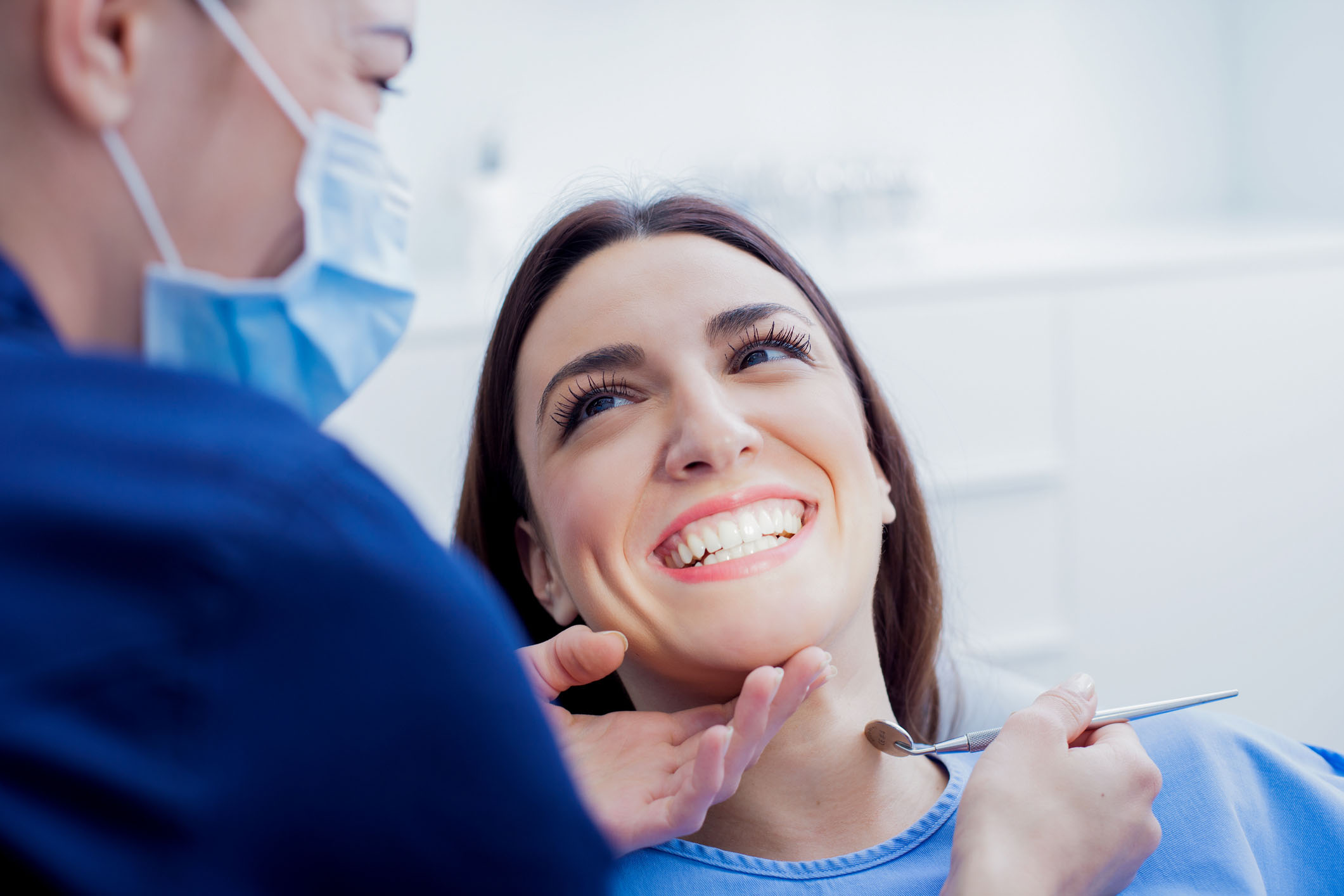 Young female patient smiling as a hygienist cleans her teeth